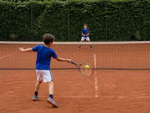 Due ragazzini durante un allenamento di tennis su un campo in terra rossa
